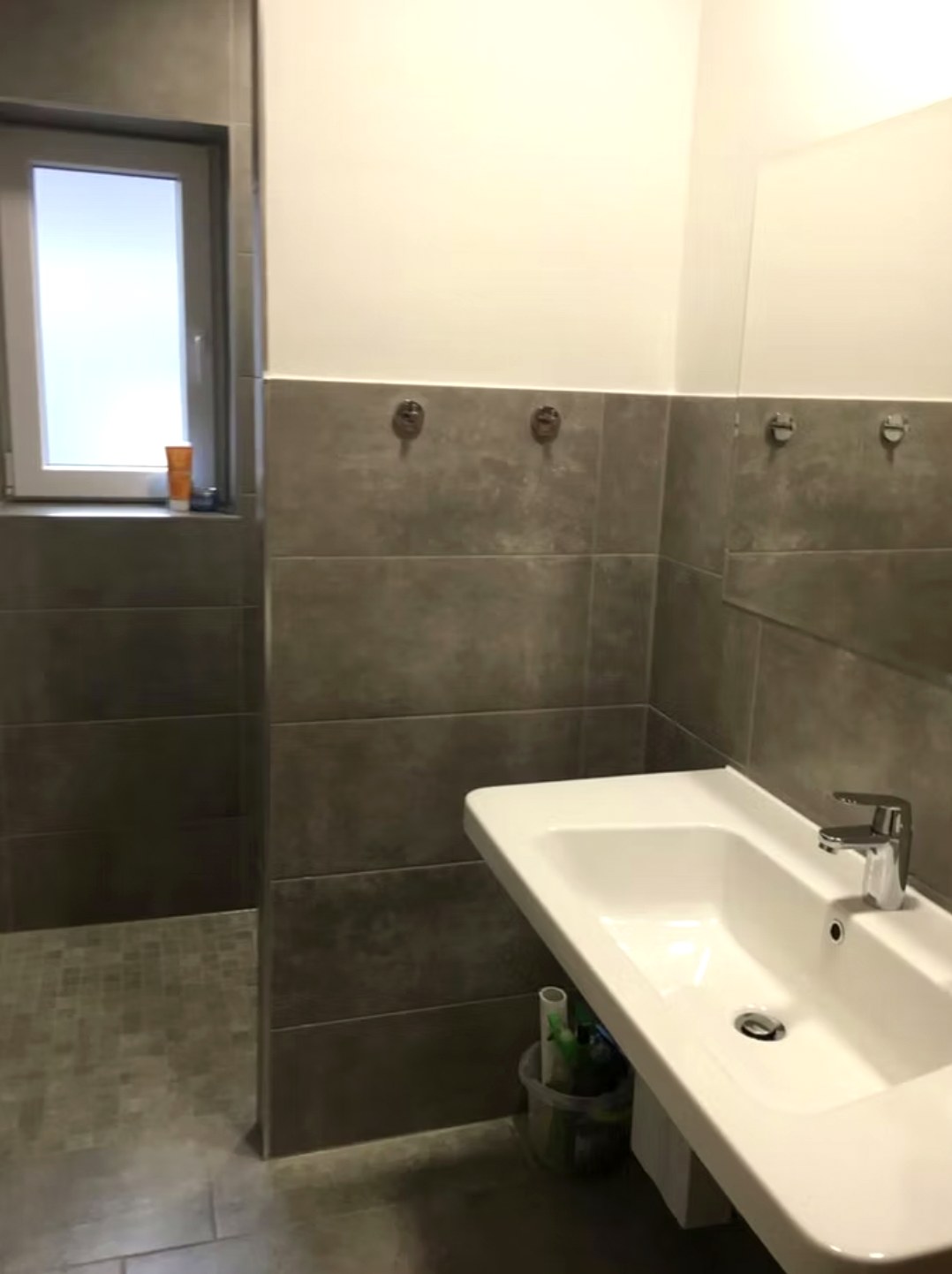 Bad im Gästehaus mit ebenerdiger Dusche und breitem Waschtisch