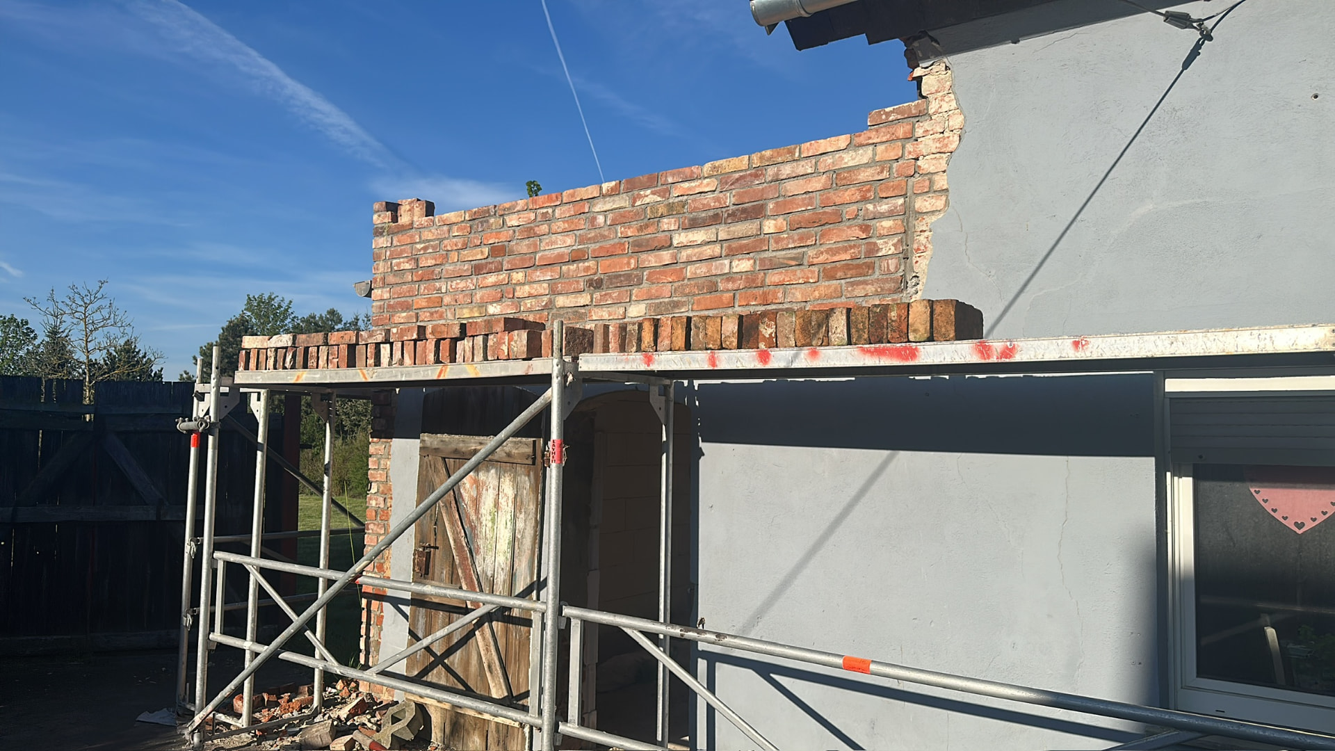 Neu aufgemauerte Wand aus alten Klinkersteinen auf The Farm, davor ein Gerüst