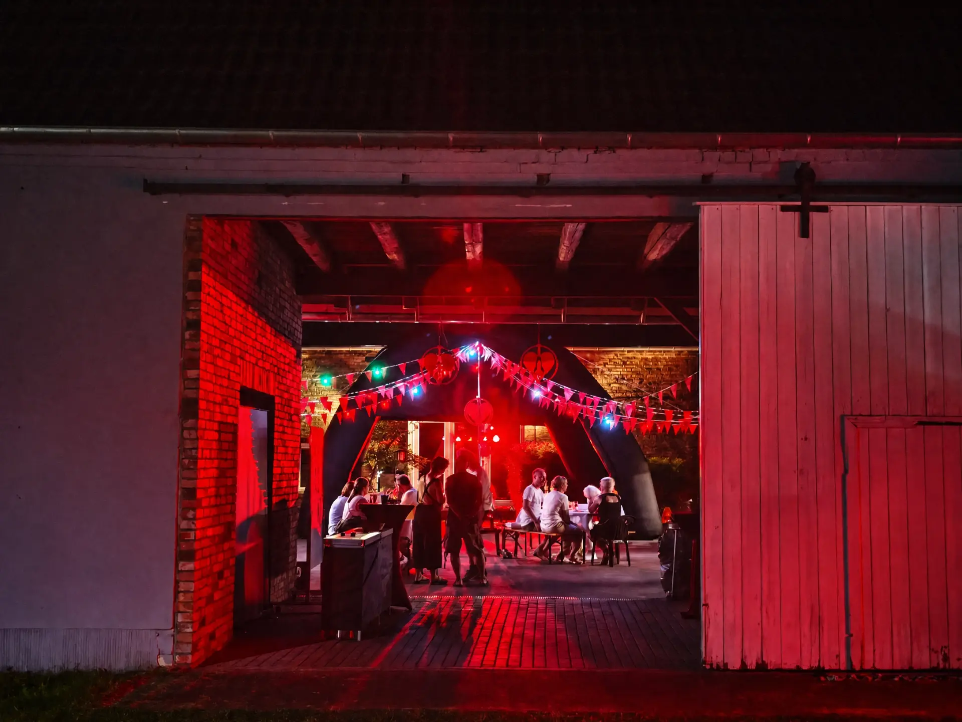Blick durch das offene Hoftor auf das Fest im rot beleuchteten Innenhof