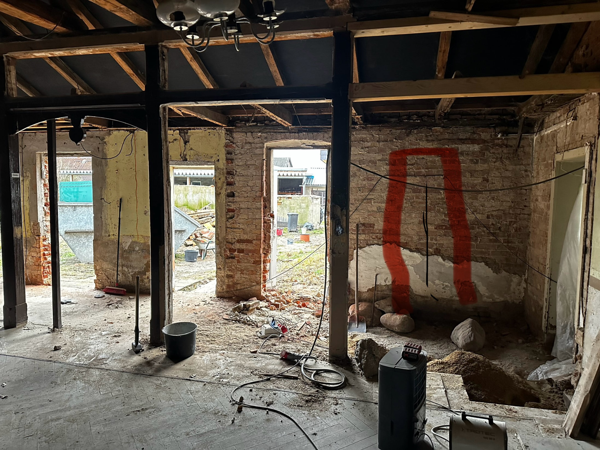 Blick in den Theatersaal von Friends im Rohbau: freigelegte Ziegelwände, rot markierte geplante Fensteröffnung und aufgestemmter Boden für neue Abflussleitungen