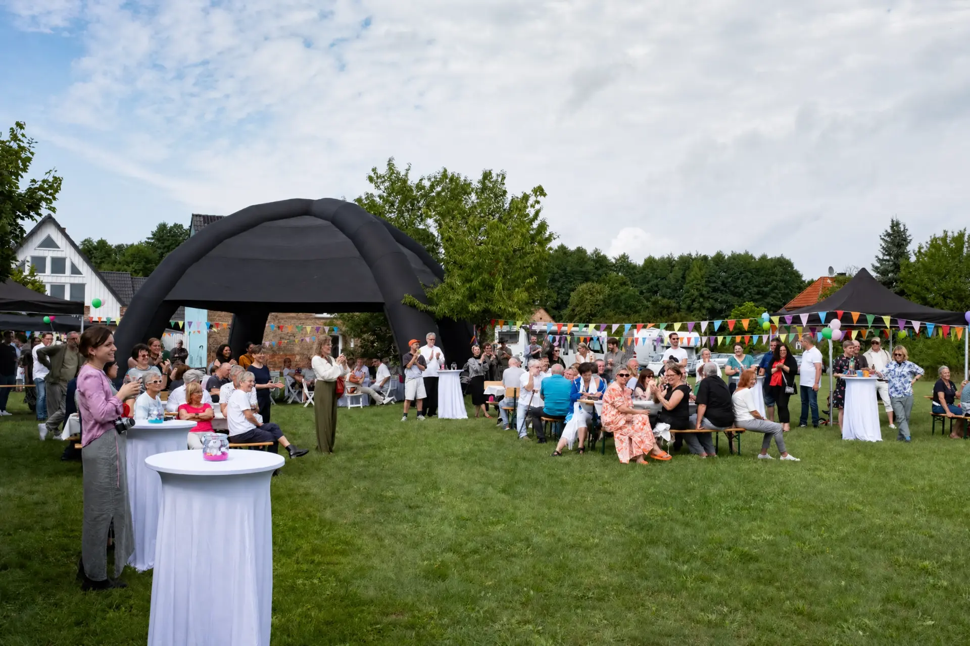 Gäste beim Gartenfest vor dem großen Pavillonzelt
