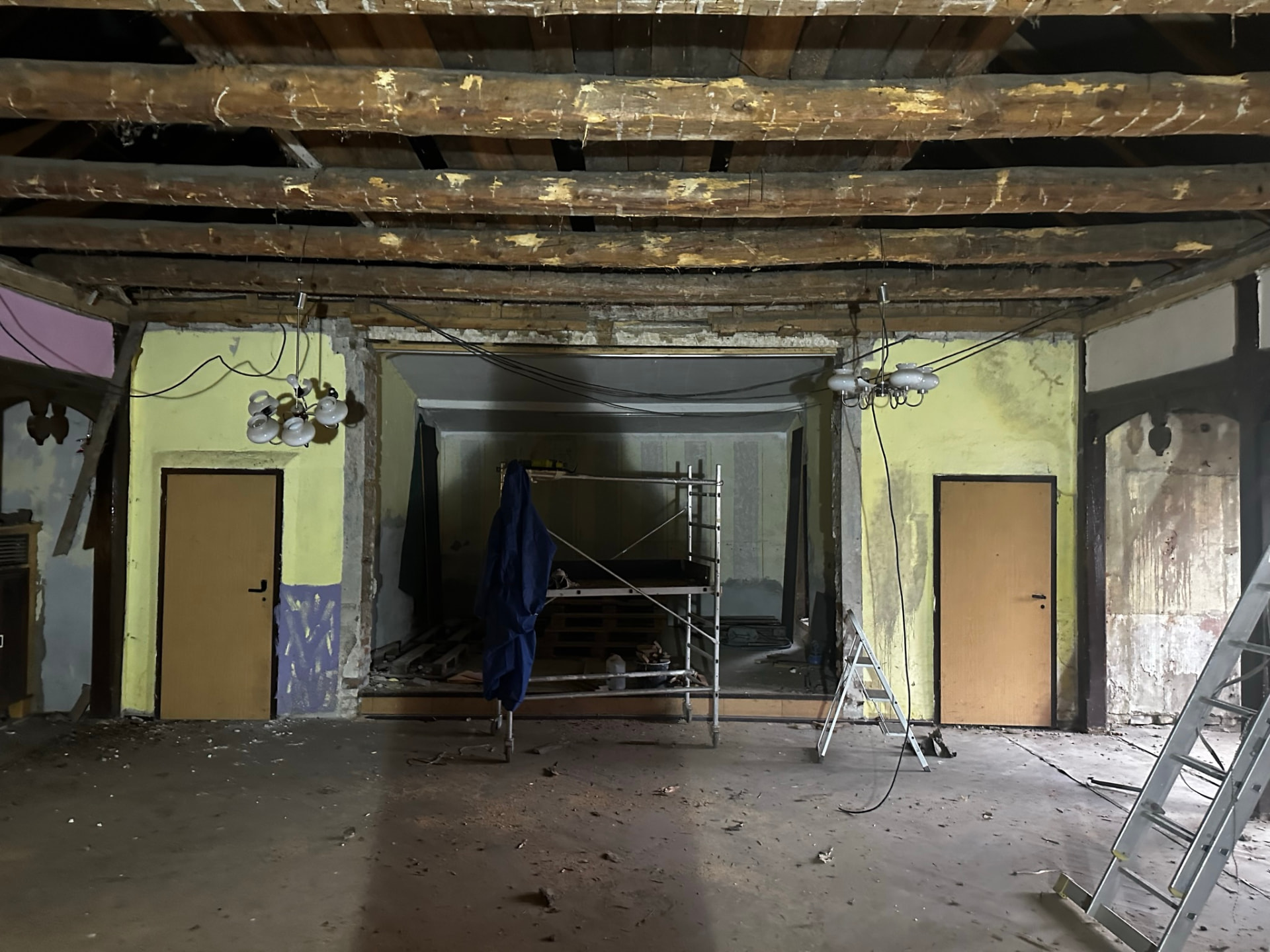 Theatersaal von Friends im Umbau: freigelegte alte Deckenbalken, entfernte abgehängte Decke, Rollgerüst und Leiter vor der Bühnenöffnung