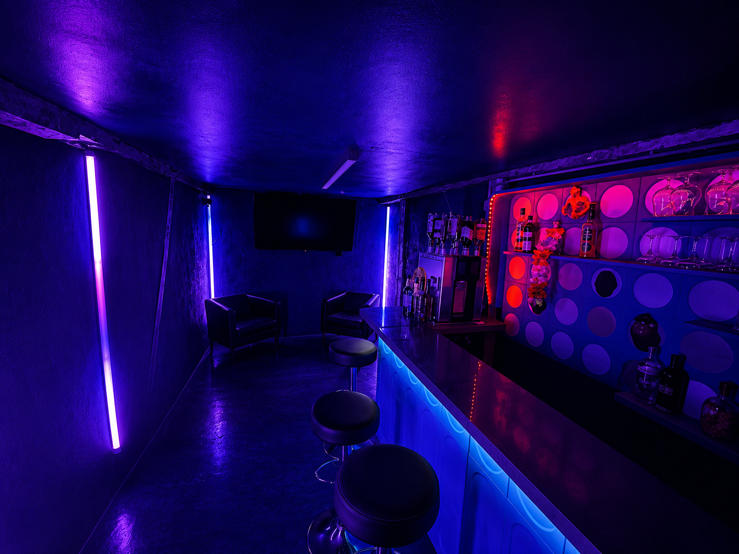 Bar im Club Kosmos in blau-violettem Neonlicht mit Barhockern und Leuchtröhren