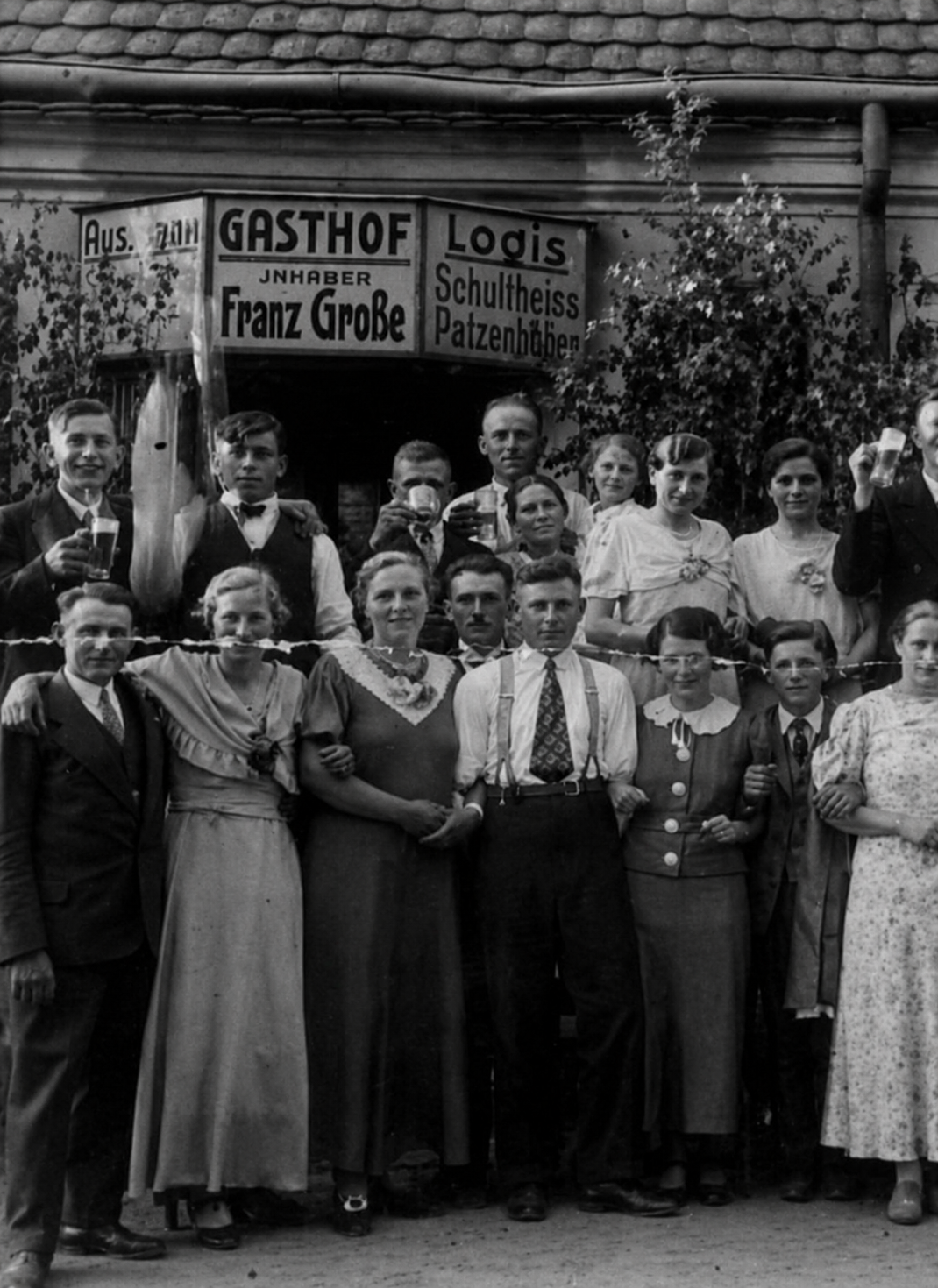 Historische Aufnahme einer Festgesellschaft vor dem Gasthof Franz Große in Bräsen, darüber die Schilder ‚Gasthof‘ und ‚Logis‘
