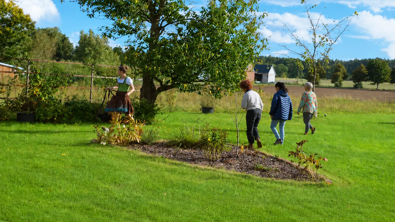 Menschen spazieren durch den Garten mit Blick über die Felder