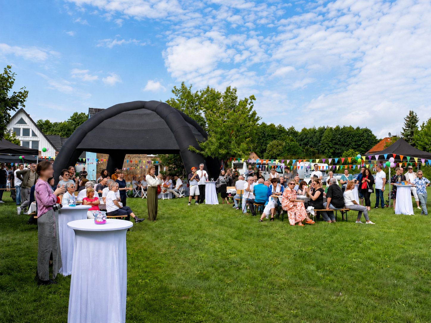 Gartenfest auf der Wiese mit Zelt, Girlanden und Gästen